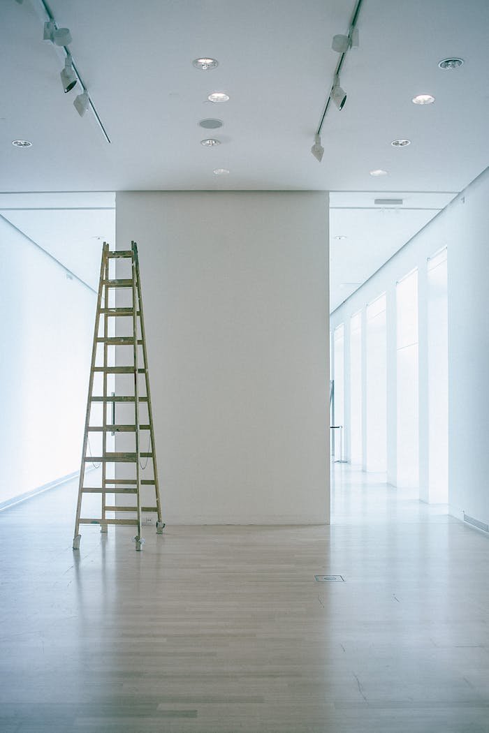 Services Wide indoor space with a ladder, showcasing LED lighting and modern minimalism.